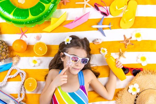 A child girl smears sunscreen on her skin. Selective focus. Kid.