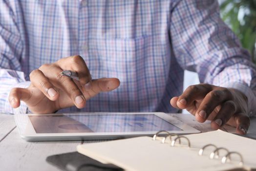 man's hand working on digital tablet at office desk, using self created chart.