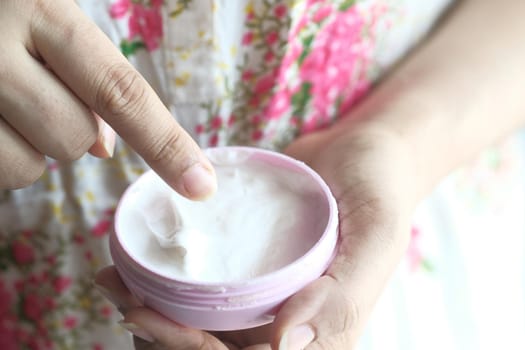 woman applying beauty cream onto skin at home top view.