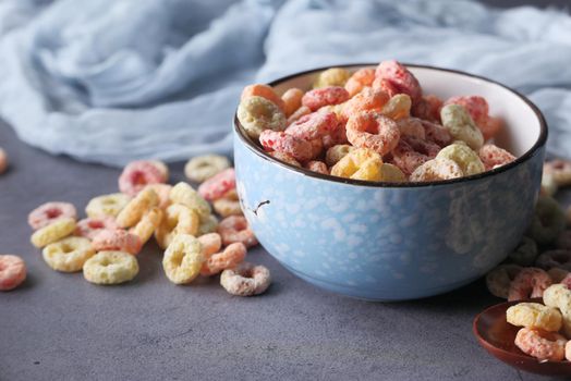 colorful ring corn flakes in a bowl on table cloth .
