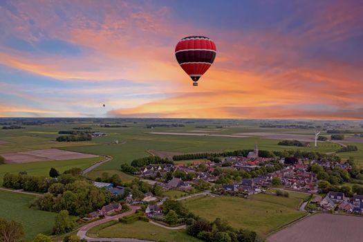 Aerial from a flying hot air balloon in the countryside from the Netherlands at sunset