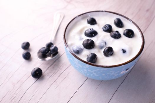 close up of fresh yogurt with blue berry in a bowl .