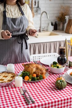 Happy Thanksgiving Day. Autumn feast. Woman celebrating holiday cooking traditional dinner at kitchen with turkey, vegetables and pumpkin pie