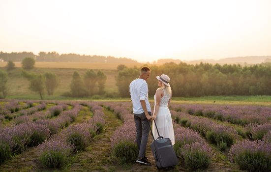 man and woman with suitcase in lavender field.