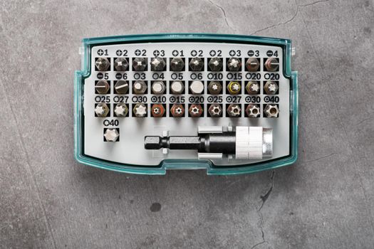 A set of metal power bits in a box on a gray background, for repair and maintenance