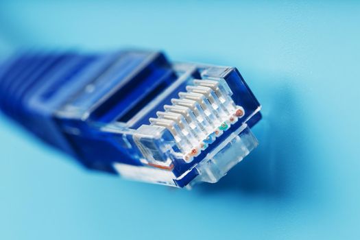 A coil of an Internet network cable for data transmission on a blue background. Patch cord for LAN cable.