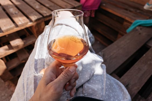 FEMALE hand holding a glass of red drink. Summer, outside