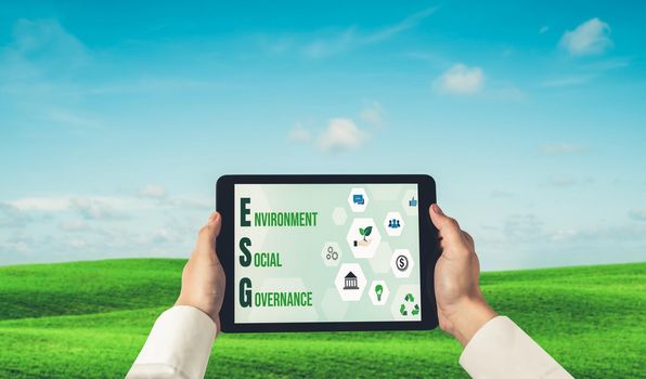 Green business transformation for environment saving and ESG business concept. Businessman using tablet to set corporate goal toward environmental friendly management and alternative clean energy use.