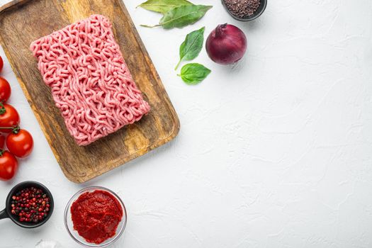 Classic italian bolognese sauce ingredients, ground meat tomatoe and herbs set, on wooden tray, on white stone background, top view, flat lay, with copy space for text