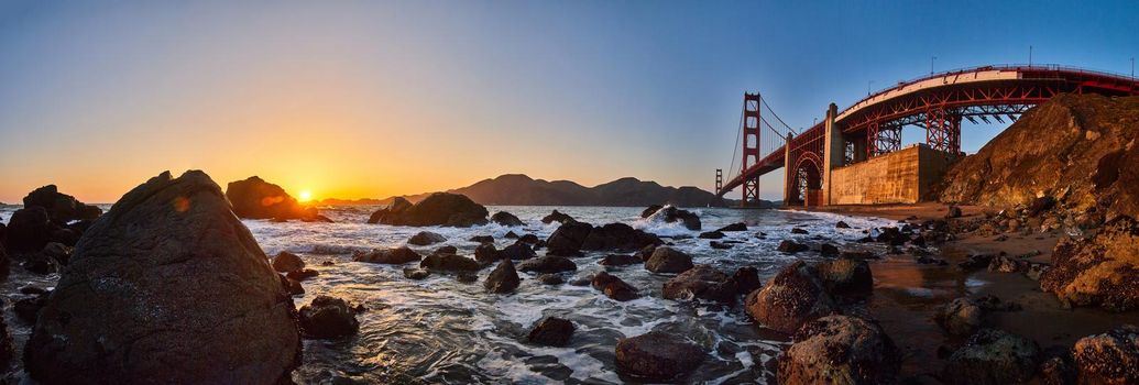 Image of Stunning panorama of Golden Gate Bridge on ocean coast with rocks and sunset