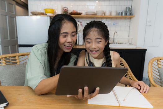 Family and home school concept. Asian mother teach her daughter using application on digital tablet at home