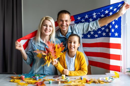 family holding american flag around autumn leaves