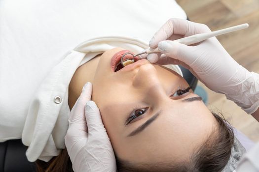 Dentist examining patient teeth with mirror in dentist clinic. Having dental checkup