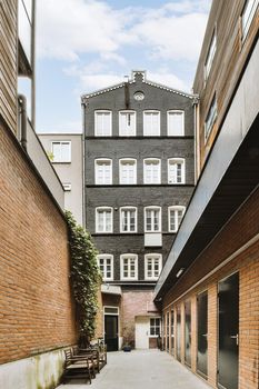 Front view of a black brick building, bicycles, chairs, sidewalk and wooden doors leading to the apartment