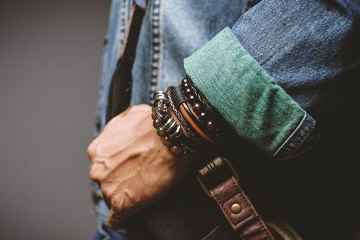 The man in jean jacket wearing bracelets, casual style of men accessories. Shallow depth of field.