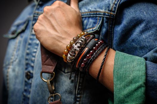 The man in jean jacket wearing bracelets, casual style of men accessories. Shallow depth of field.