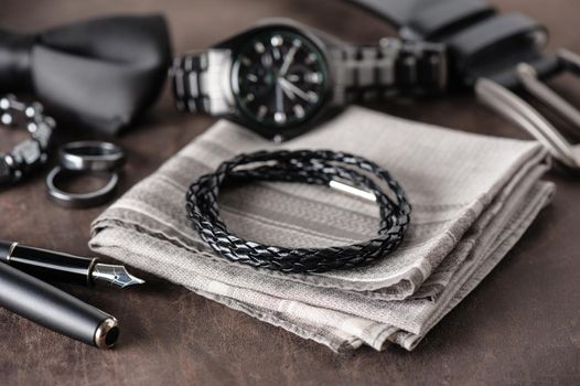 closeup black braided leather bracelet for men, casual style of men accessories. Shallow depth of field.