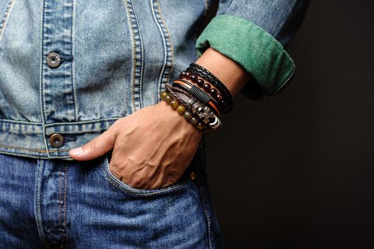 The man in jean jacket wearing bracelets, casual style of men accessories. Shallow depth of field.