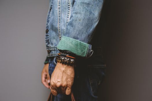 The man in jean jacket wearing bracelets, casual style of men accessories. Shallow depth of field.