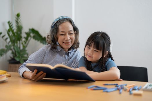 grandchild granddaughter grandma grandmother reading book girl senior.