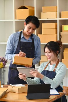 Two young start up business partner working and preparing parcel boxes of product for shipment.