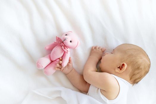 Baby sleeps with a teddy bear on a white background. Selective focus. People.