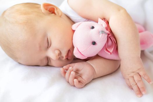 Baby sleeps with a teddy bear on a white background. Selective focus. People.