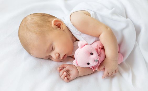 Baby sleeps with a teddy bear on a white background. Selective focus. People.