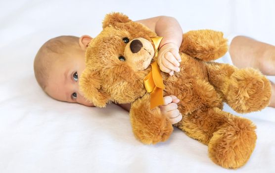 Baby plays with teddy bear against white background. Selective focus. People.