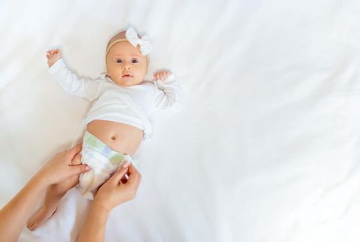 Mom is changing the baby's diaper. Selective focus. People.