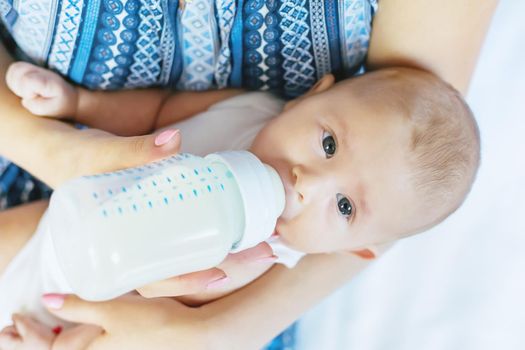 Mom feeds the baby with a bottle. Selective focus. People.