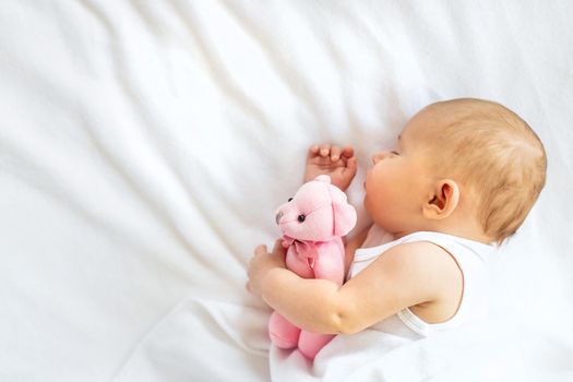 Baby sleeps with a teddy bear on a white background. Selective focus. People.