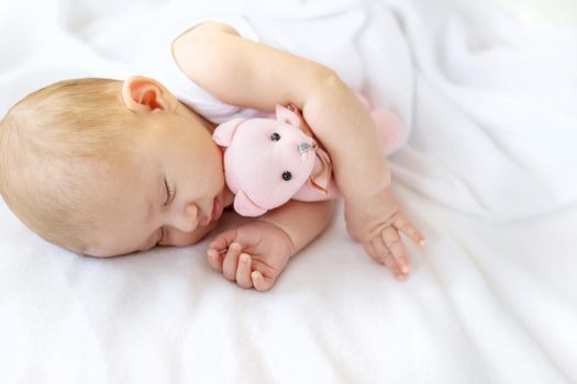 Baby sleeps with a teddy bear on a white background. Selective focus. People.
