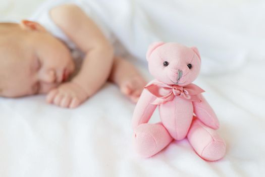 Baby sleeps with a teddy bear on a white background. Selective focus. People.