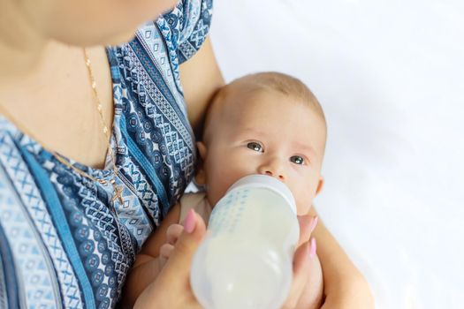 Mom feeds the baby with a bottle. Selective focus. People.