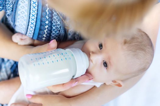 Mom feeds the baby with a bottle. Selective focus. People.