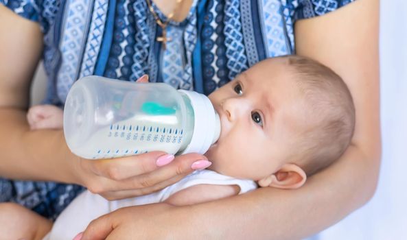 Mom feeds the baby with a bottle. Selective focus. People.