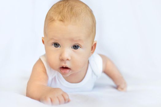 Baby lies on her stomach on a white background. Selective focus. People.