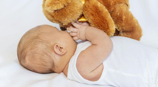 Baby plays with teddy bear against white background. Selective focus. People.