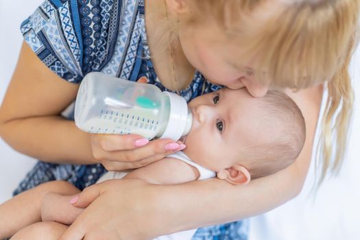 Mom feeds the baby with a bottle. Selective focus. People.