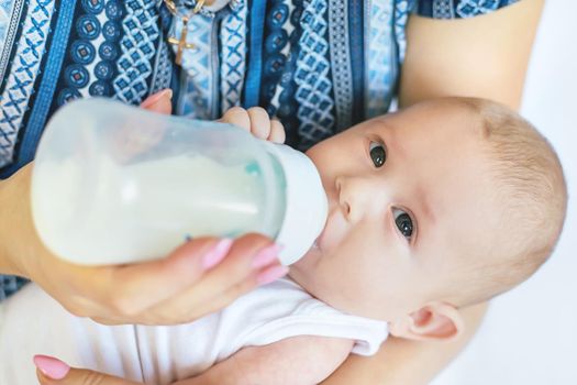 Mom feeds the baby with a bottle. Selective focus. People.