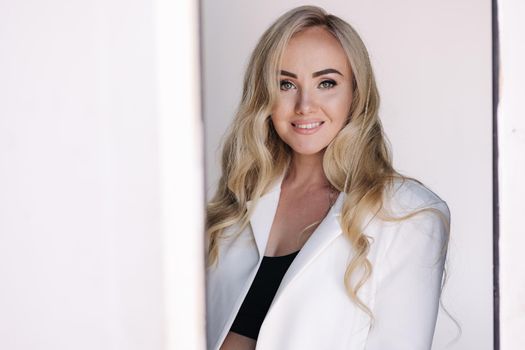 Portrait of pregnant woman in studio on white background. Beautiful future mother put her her hands on her belly. Blond hair woman in white jaket.