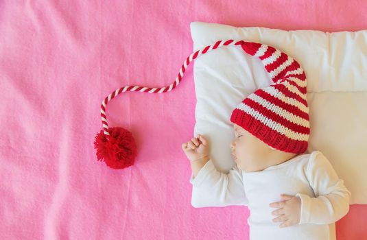 Baby sleeps in a Santa hat. Selective focus. People. Merry Christmas and Happy New Year, Holidays greeting card background. Selective focus.