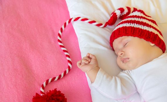 Baby sleeps in a Santa hat. Selective focus. People. Merry Christmas and Happy New Year, Holidays greeting card background. Selective focus.