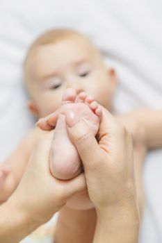 The mother keeps the baby's leg at home. Selective focus. People.