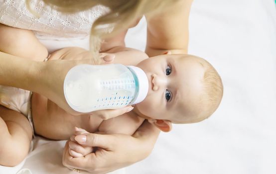 Mom feeds the baby with a bottle. Selective focus. People.