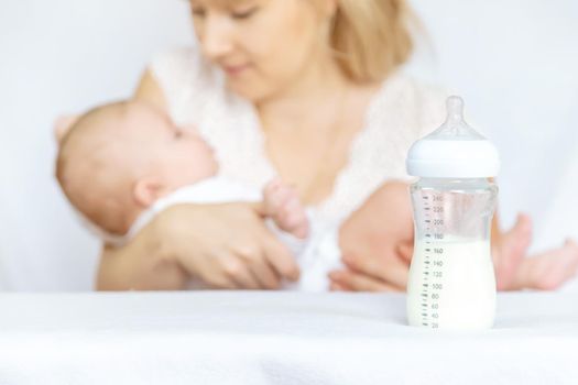 Mother feeds the baby from a bottle. Selective focus. People.