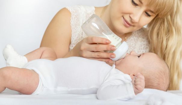 Mother feeds the baby from a bottle. Selective focus. People.