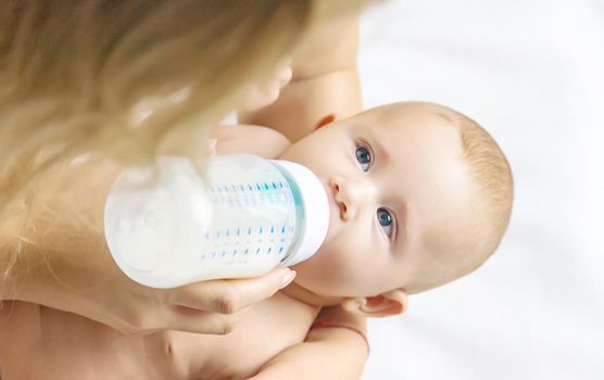 Mom feeds the baby with a bottle. Selective focus. People.