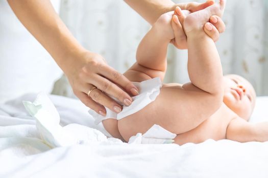 The mother changes the baby's diaper. Selective focus. People.